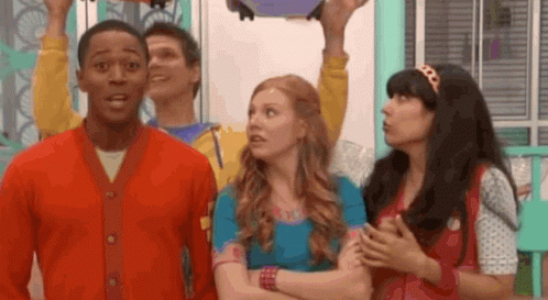 A Group Of People Are Standing Next To Each Other In A Room And One Of Them Is Holding Something In His Hand . GIF