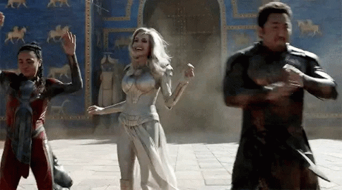 A Group Of People Are Standing Next To Each Other In Front Of A Building And Dancing . GIF