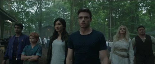 A Group Of People Are Standing Next To Each Other In The Woods GIF