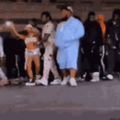 A Group Of People Are Standing Next To Each Other On The Street . GIF