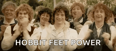 A Group Of People Are Standing Next To Each Other With Their Hands In The Air And The Words `` Hobbit Feet Power '' . GIF