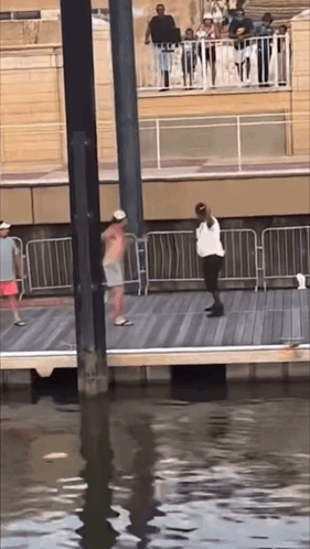 A Group Of People Are Standing On A Pier Overlooking The Water GIF
