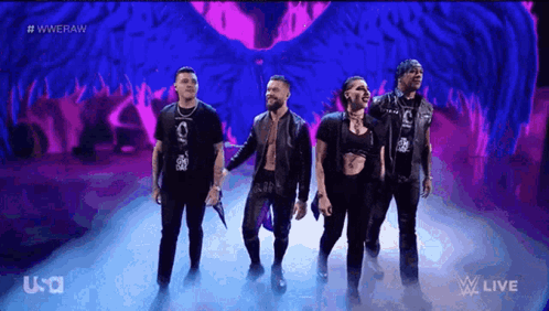 A Group Of People Are Standing On A Stage In Front Of A Purple Background That Says Wwe Raw GIF
