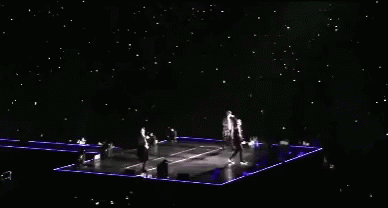 A Group Of People Are Standing On A Stage With A Lot Of Lights On It GIF