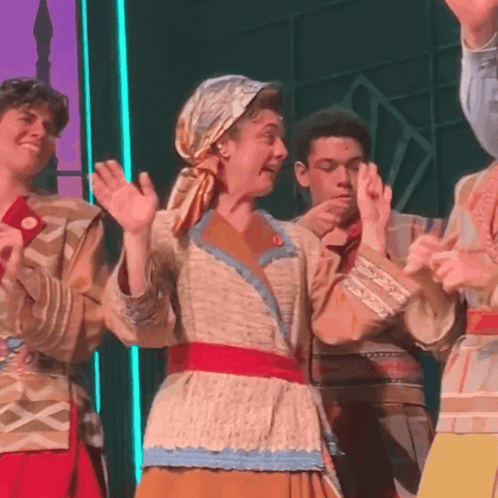 a group of people are standing on a stage with their hands up