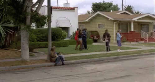 A Group Of People Are Standing On The Side Of A Street In Front Of A House . GIF