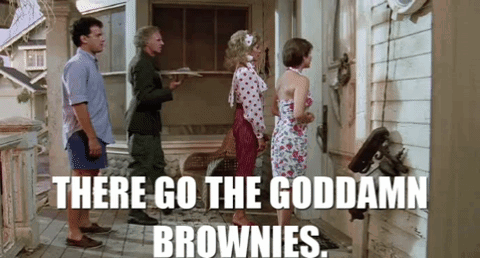 A Group Of People Are Standing Outside Of A House And A Man Is Holding A Tray Of Brownies . GIF