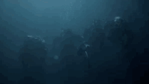 a group of people are swimming in the ocean with bubbles coming out of the water .