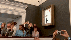 A Group Of People Are Taking Pictures Of A Painting Of A Girl With A Red Heart GIF