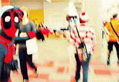 A Group Of People Are Walking Down A Hallway And One Of Them Is Dressed In A Deadpool Costume . GIF
