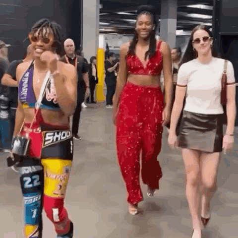 A Group Of People Are Walking Down A Hallway And One Of Them Is Wearing A Crop Top With The Number 22 On It . GIF