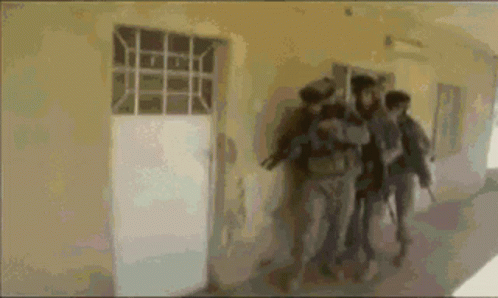 A Group Of People Are Walking Down A Hallway Holding Guns GIF
