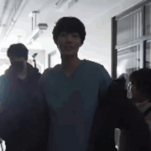 A Group Of People Are Walking Down A Hallway . GIF