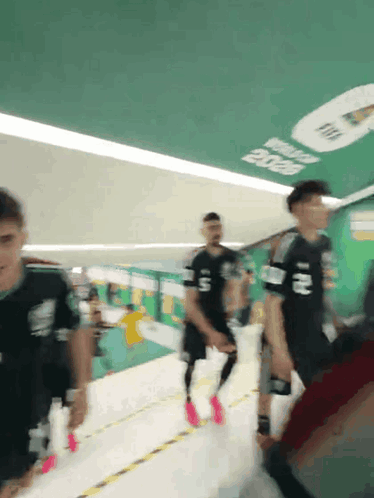 a group of people are walking down a hallway with a sign on the ceiling that says fifa 2020