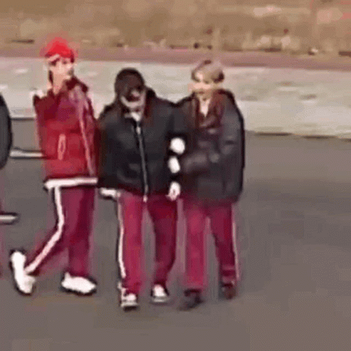 a group of people are walking down a street and one of them is holding another person 's arm .