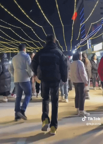 A Group Of People Are Walking Down A Street At Night With A Tiktok Watermark GIF