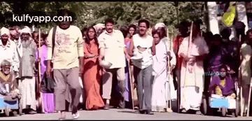 A Group Of People Are Walking Down A Street In A Crowded Area . GIF