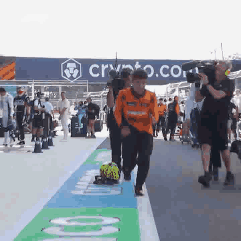 A Group Of People Are Walking Down A Street In Front Of A Sign That Says Crypto . GIF