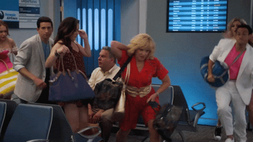 A Group Of People Are Walking In Front Of A Screen That Says Departures GIF