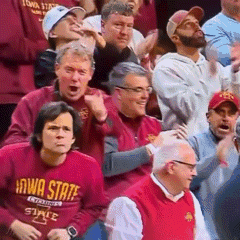 a group of people are watching a basketball game and one of them is wearing a iowa state shirt