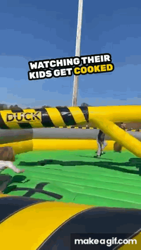 a group of people are watching their kids get cooked at an inflatable duck .