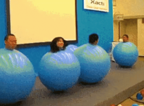 A Group Of People Are Wrapped In Blue Balloons In Front Of A Sign That Says Xact GIF