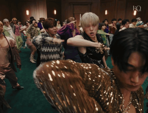 a group of people dancing in a room with the letter q on the bottom right