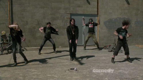 A Group Of People Dancing In Front Of A Comedy Sign GIF
