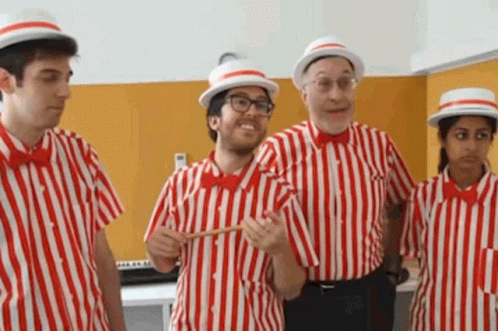 a group of people dressed in red and white striped shirts and hats are standing next to each other .
