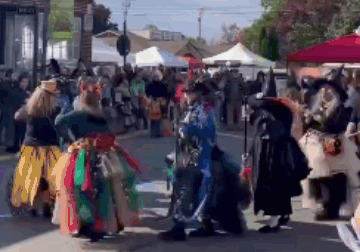 A Group Of People Dressed Up As Witches Are Dancing On A Street . GIF