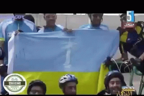 A Group Of People Holding A Flag With The Number 5 On The Bottom Right GIF
