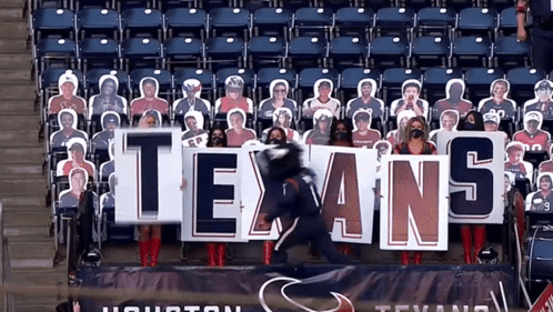 A Group Of People Holding A Texans Sign In A Stadium GIF