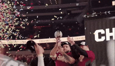 a group of people holding a trophy in front of a banner that says champion