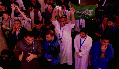 a group of people holding up a green flag with arabic writing