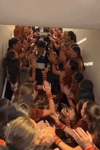 A Group Of People In A Hallway With The Word Lacoste Written On The Wall GIF