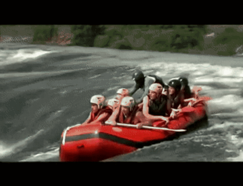 A Group Of People In A Red Raft Going Through A River GIF