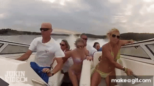 A Group Of People In Bikinis Are Riding A Boat In The Water . GIF