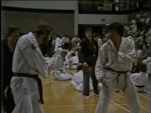 A Group Of People In Karate Uniforms Are Standing On A Court GIF