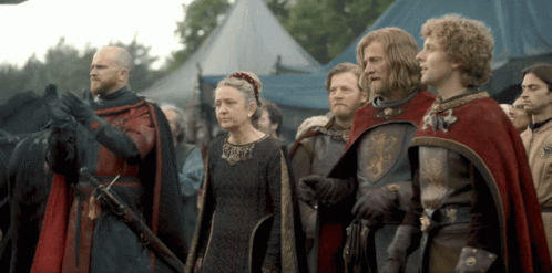 A Group Of People In Medieval Costumes Stand In Front Of A Blue Tent GIF