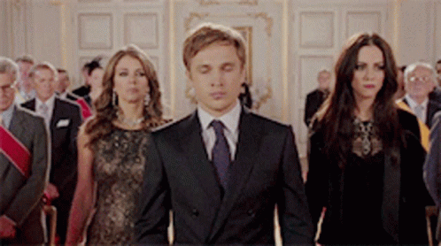 A Group Of People In Suits And Ties Are Walking In A Room GIF