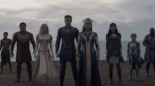 A Group Of People In Superhero Costumes Stand On A Beach GIF