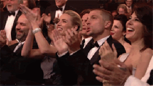 A Group Of People In Tuxedos Are Clapping Their Hands In A Crowd . GIF