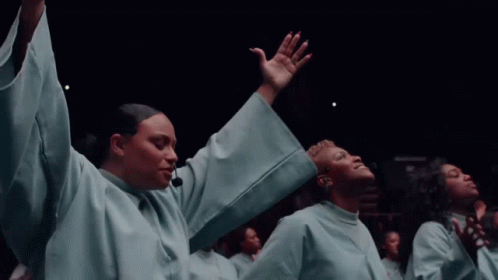 A Group Of People In White Robes Are Raising Their Hands In The Air GIF
