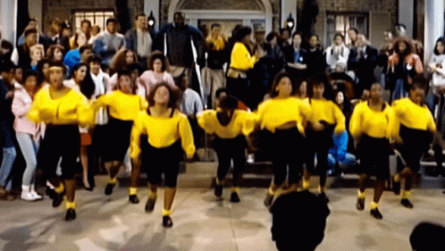 A Group Of People In Yellow Sweaters Are Dancing GIF