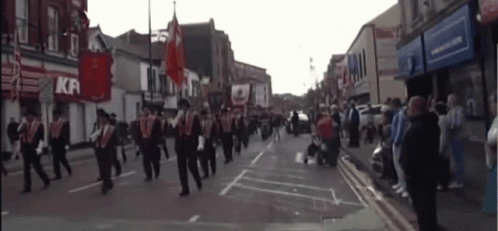 A Group Of People March Down A Street In Front Of A Kfc GIF