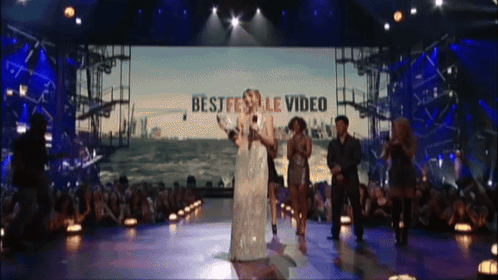 A Group Of People On A Stage With The Words Best Festival Video On The Screen Behind Them GIF