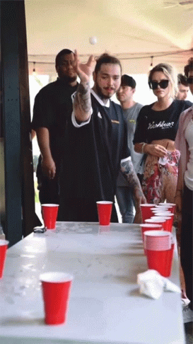A Group Of People Playing Beer Pong With Red Cups On A Table GIF
