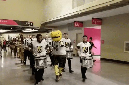 A Group Of People Playing Drums In A Hallway With A Sign That Says Men 'S And Women 'S Restrooms GIF