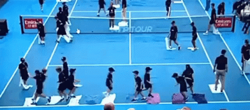 a group of people playing tennis on a blue court with emirates advertisements