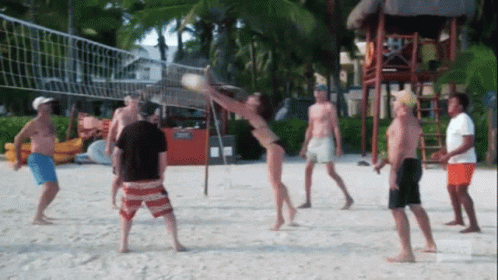 A Group Of People Playing Volleyball On The Beach GIF